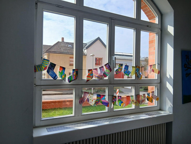 Auf diesem Bild sieht man gemalte Socken an einem Fenster.