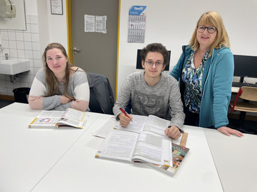 Af diesem Bild sieht man eine Lerngruppe mit ihrer Lehrerin.