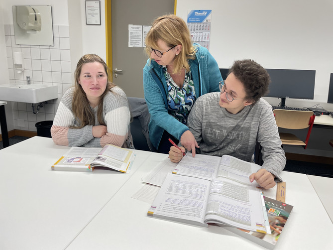Auf diesem Bild sieht man eine Lehrerin mit zwei Schülern.