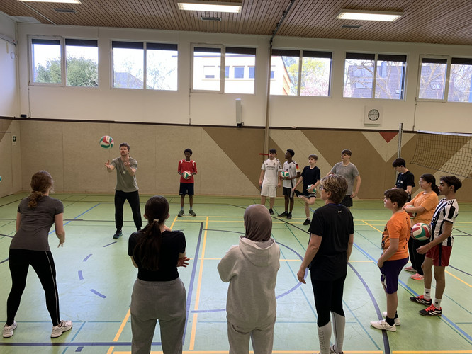 Auf diesem Bild spielt eine Schülergruppe Volleyball.
