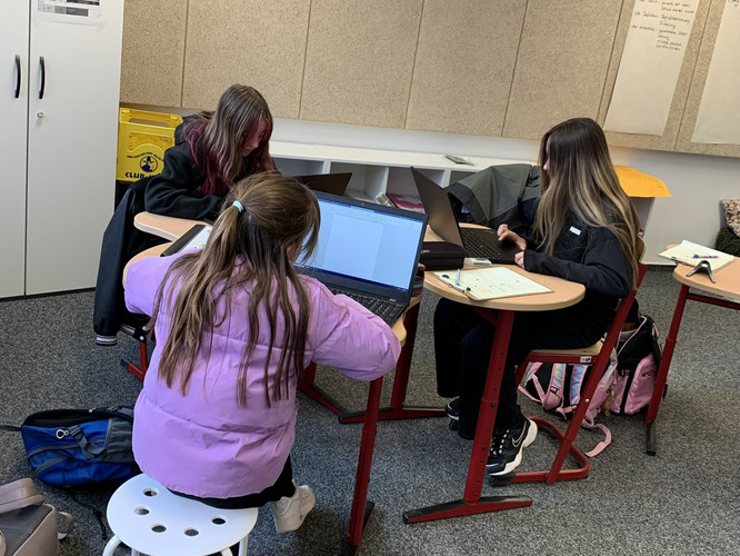 Auf diesem Bild sieht man drei Schülerinnen an Laptops.